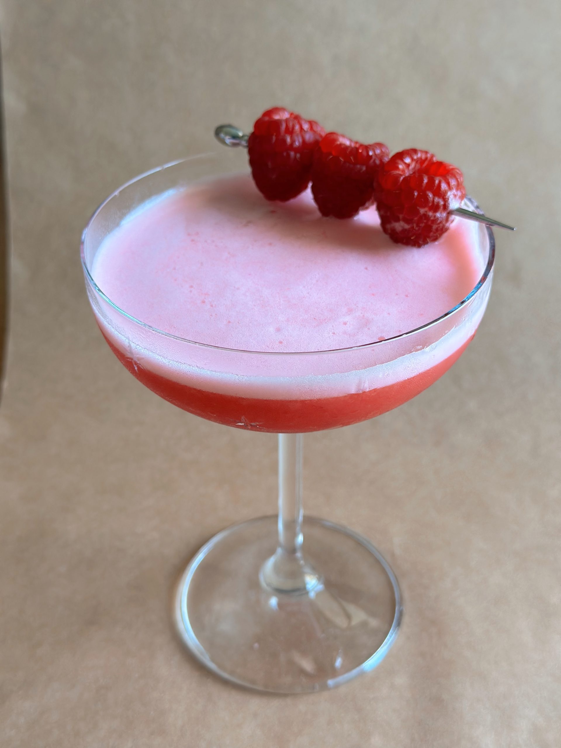 Non-alcoholic Clover Club cocktail in a coupe glass with raspberry garnish