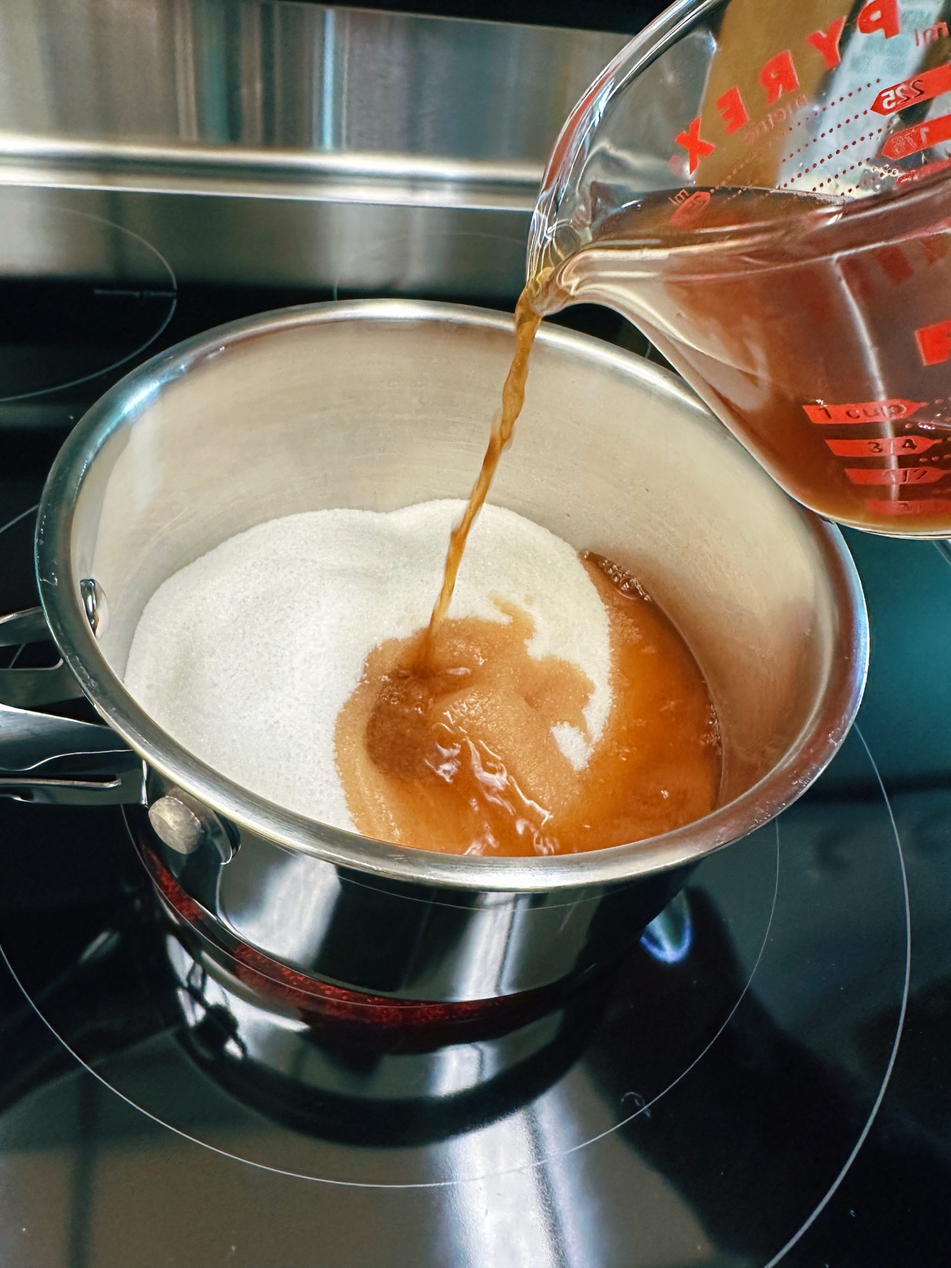 Adding vinegar to a saucepan with sugar to make a shrub using the hot method