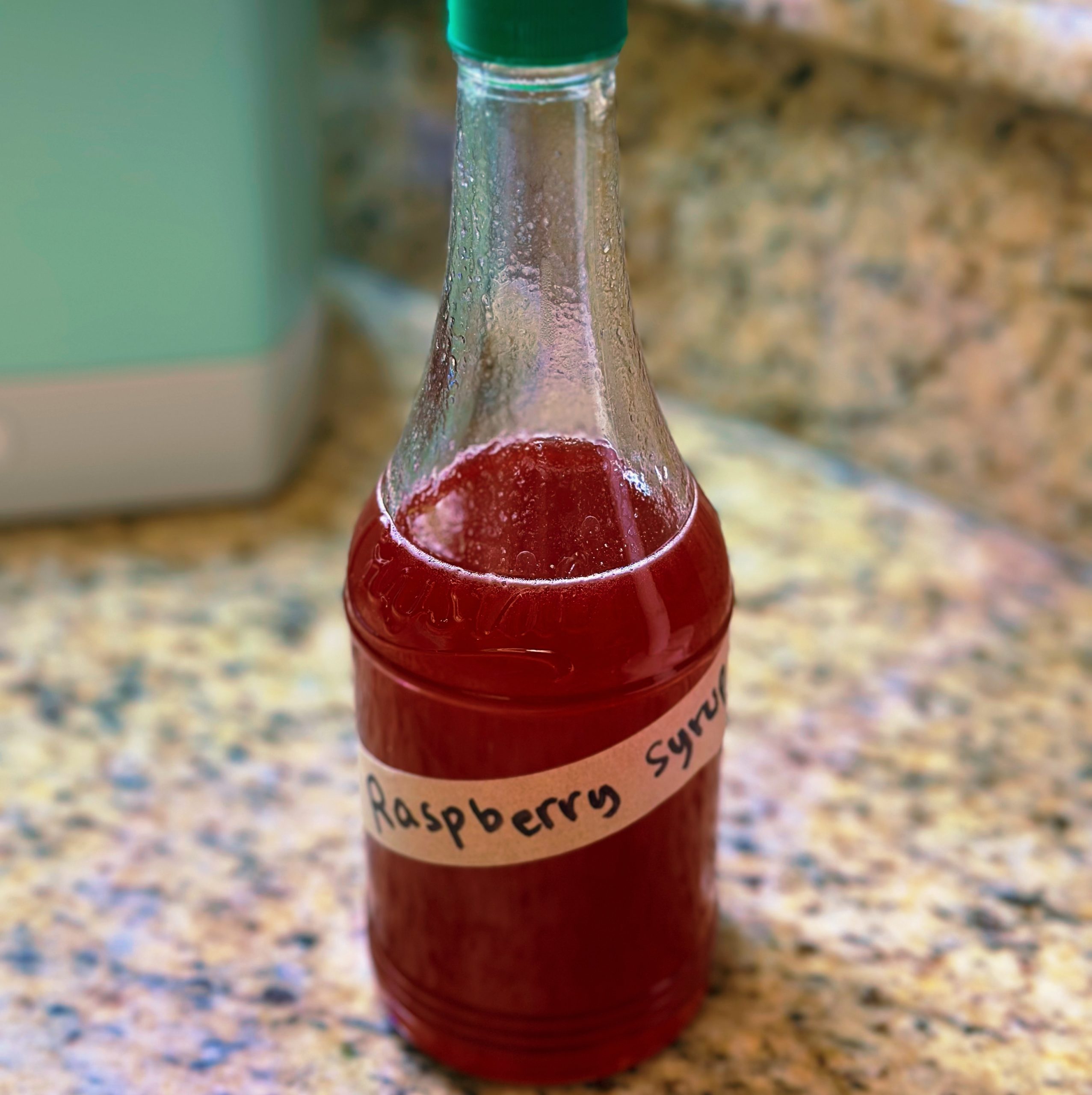 Recycled glass bottle filled with homemade raspberry syrup.